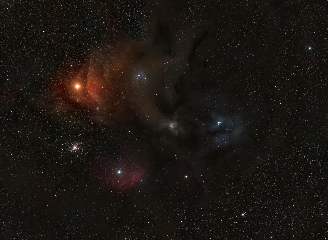 A colorful field around Antares with dusty reflection nebulae, dark lanes, and the warm glow of the Rho Ophiuchi cloud complex.
