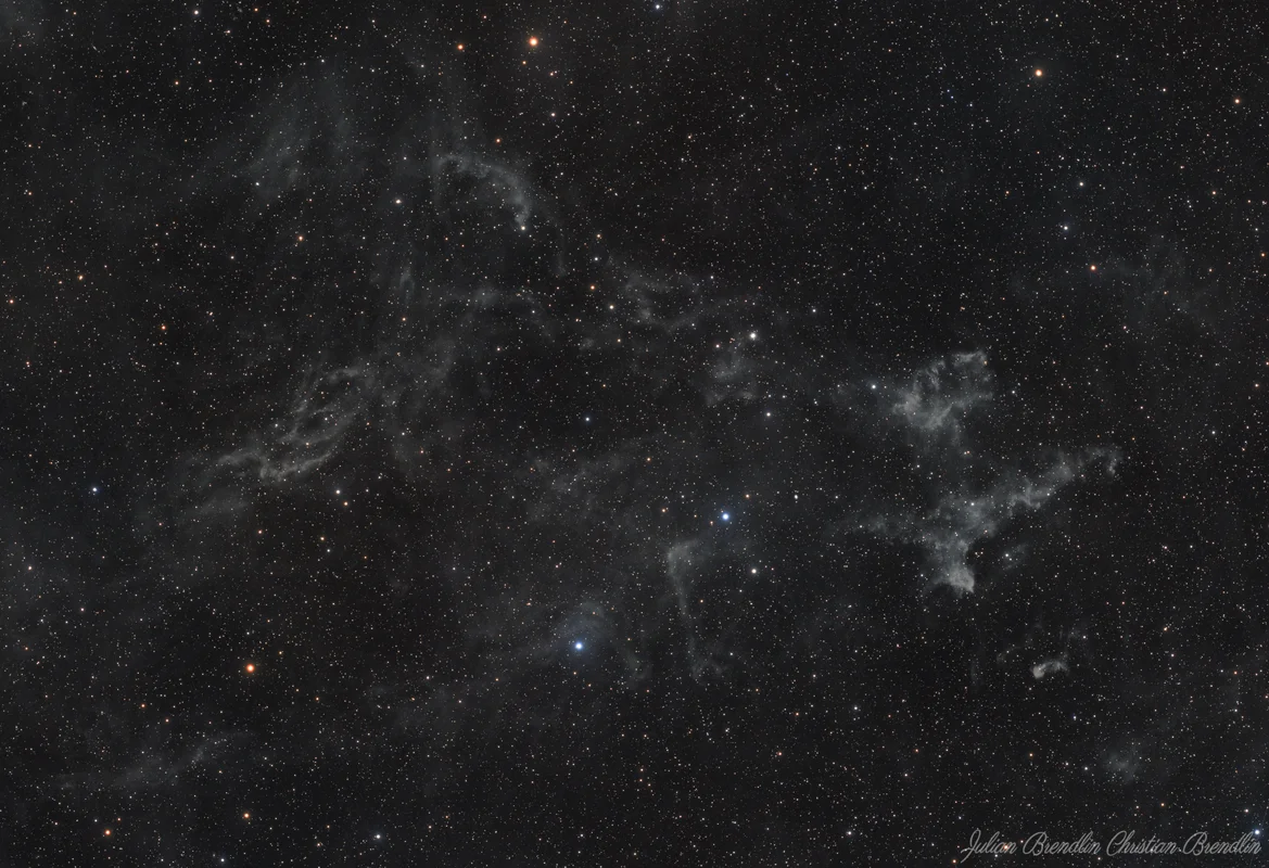 A faint nebula region captured with emphasis on delicate structure, soft contrast, and the surrounding star field.